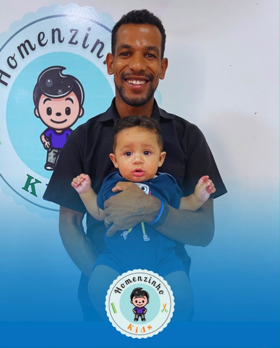 Barbeiro da Homem.com segurando um bebê após o corte