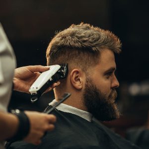 young-bearded-man-getting-haircut-by-hairdresser-6RCT7CV.jpg